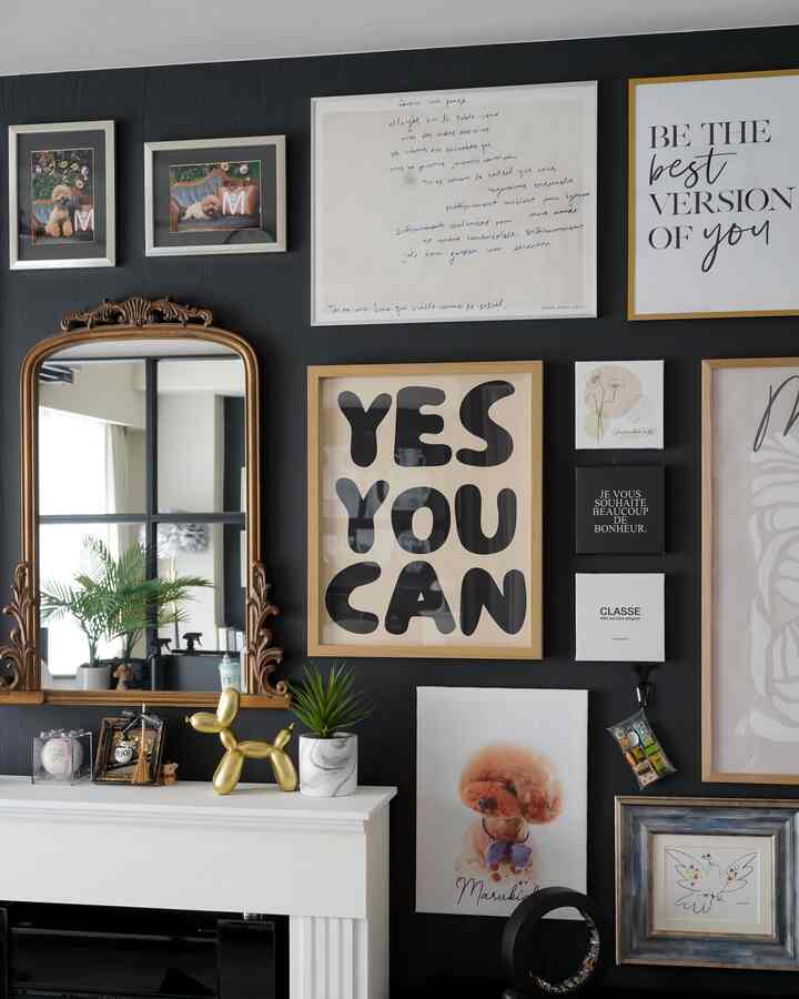 ゴールドの装飾と複数の額が掛けられた暗い壁のリビングスペース