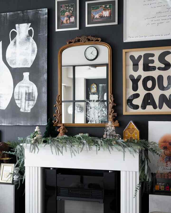 ゴールドフレームの鏡と多様な額縁が黒い壁に配置されたナチュラルな雰囲気の暖炉空間