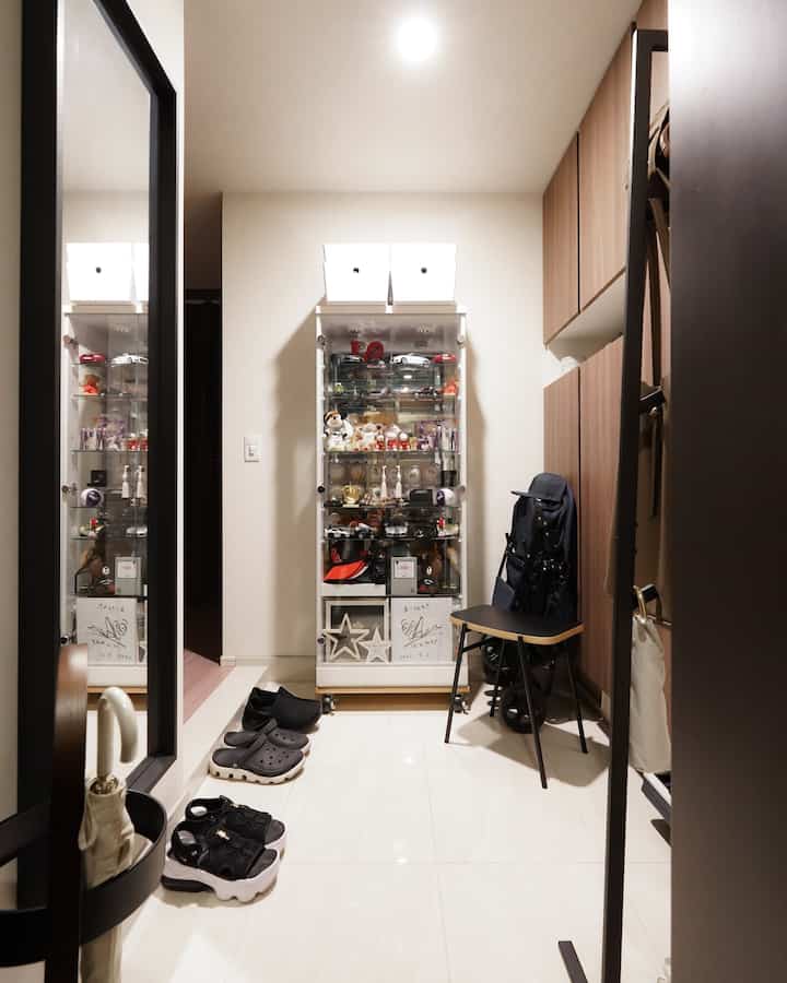 白と茶色のトーンの狭い玄関、靴と木目調の収納キャビネットが配置された清潔感のある空間