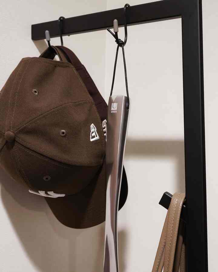 黒いコートハンガーに茶色の帽子とシューホーンが掛けられた玄関のクローズアップ