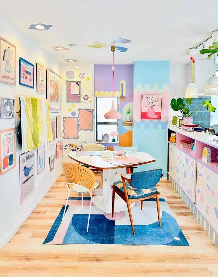 パステルトーンと木目調が調和したダイニングルーム、多様なデザインの椅子と印象的な壁アートが配置された雰囲気のあるインテリア