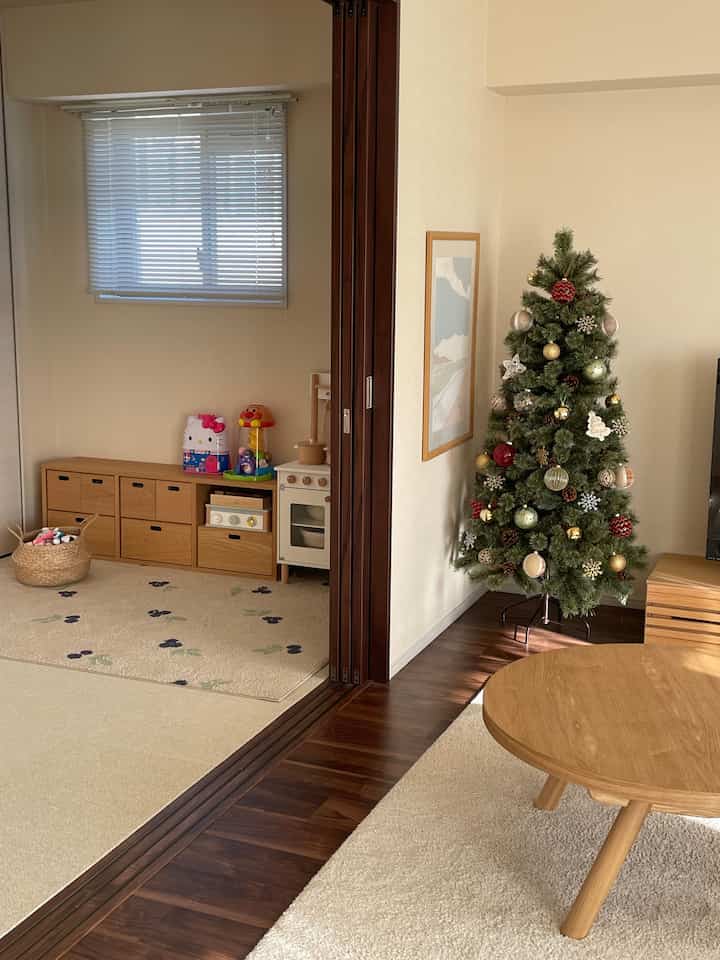 ナチュラルな色調のリビングと子供部屋が仕切られ、木製家具と飾られたクリスマスツリーがある温かみのあるインテリア