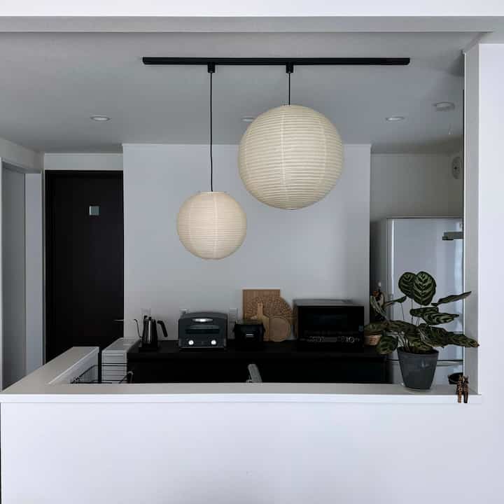 白と黒のトーンのキッチン空間、中央にペンダントライトが配置され、木製アクセサリーでナチュラルな雰囲気を加えた印象的なインテリア
