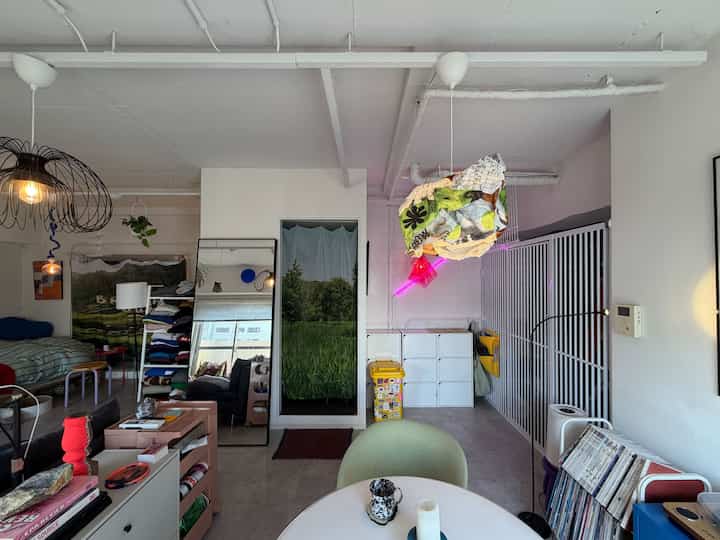 明るいホワイトトーンのダイニングルーム、様々な照明と収納棚、ユニークな布のカーテンが調和した雰囲気のあるインテリア