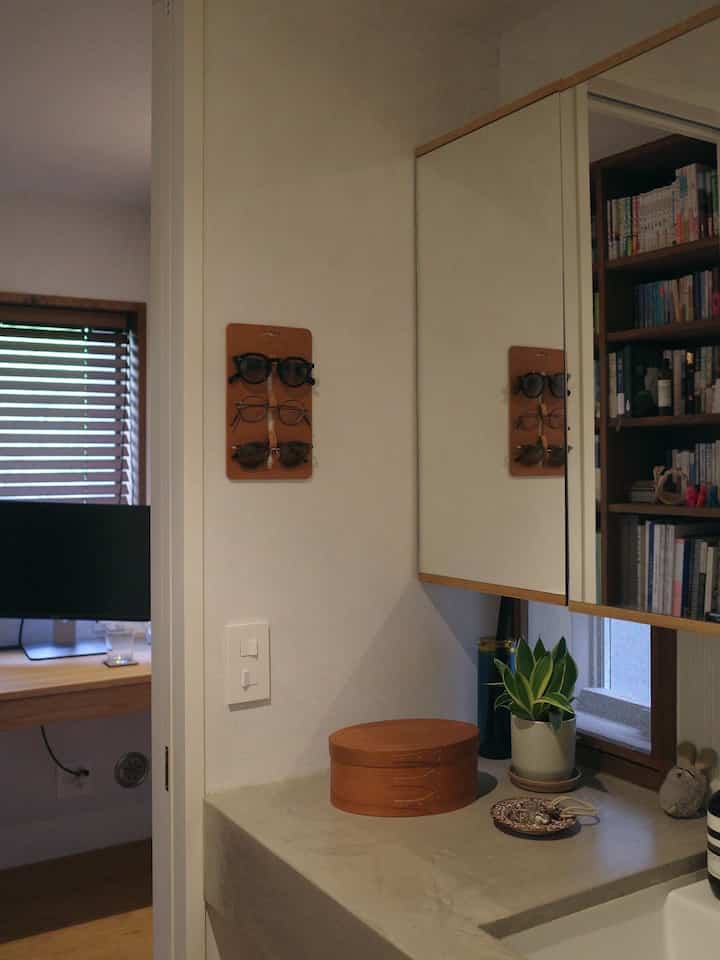 白とナチュラルトーンの化粧台エリア、ヴィンテージボックスと植物が配置された雰囲気のあるインテリア