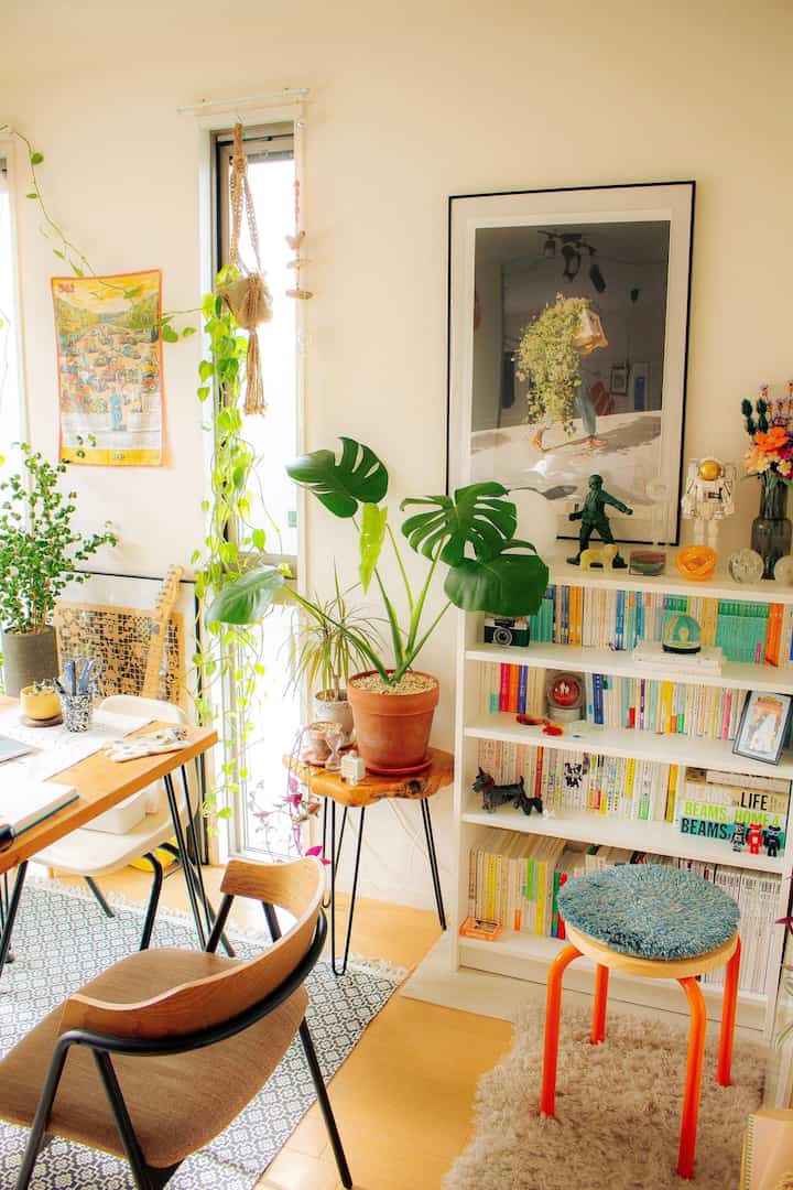 ホワイトとブラウンの色調のダイニングルーム、植物と本棚が配置された自然で落ち着いた雰囲気のインテリア