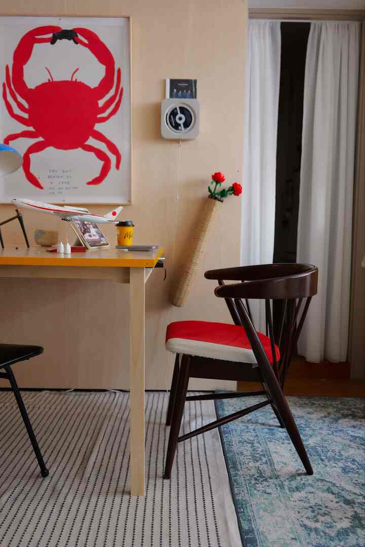 ナチュラルな色調のワークスペース、赤いクッション付きの椅子と机が置かれた雰囲気のあるインテリア