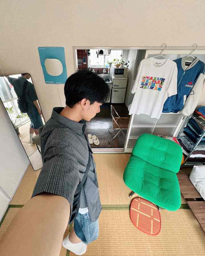 緑のアームチェアが置かれた狭い和モダンのワンルーム、畳床とミニマルなインテリアが印象的な空間