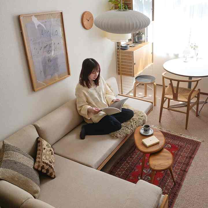暖かいベージュトーンのリビング、ベージュのファブリックソファとヴィンテージのキリムラグ、木製のコーヒーテーブルが配置された雰囲気のあるインテリア