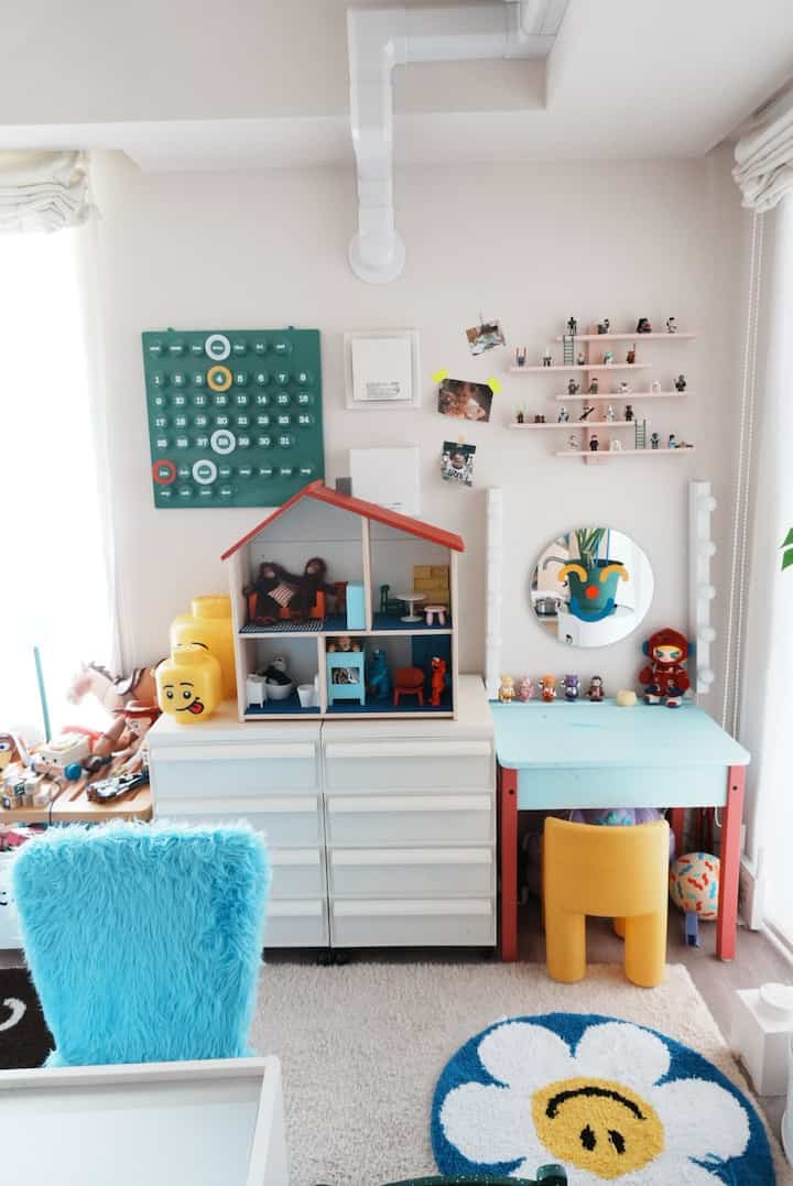白と青の色調の子供部屋、ドールハウスと鏡付きの子供用デスクが配置された雰囲気のあるインテリア