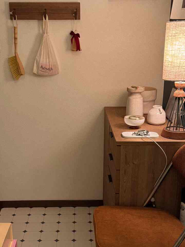 ベージュとブラウンの色調が特徴の玄関コーナー、木製の壁掛けと装飾品が配置された温かみのある雰囲気の空間