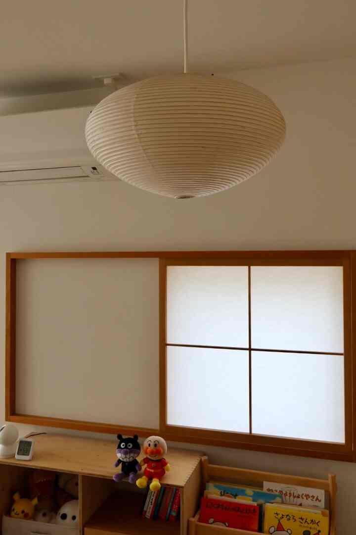 柔らかな白色と木目調の正方形の子供部屋、ペンダントライトと本棚が配置された雰囲気のあるインテリア