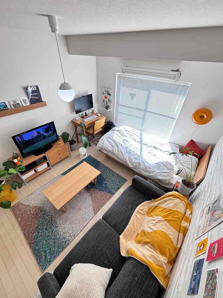 ナチュラルな色調の7畳ワンルーム、木目調家具とコンパクトなホームオフィス、観葉植物が配置された温かみのある空間