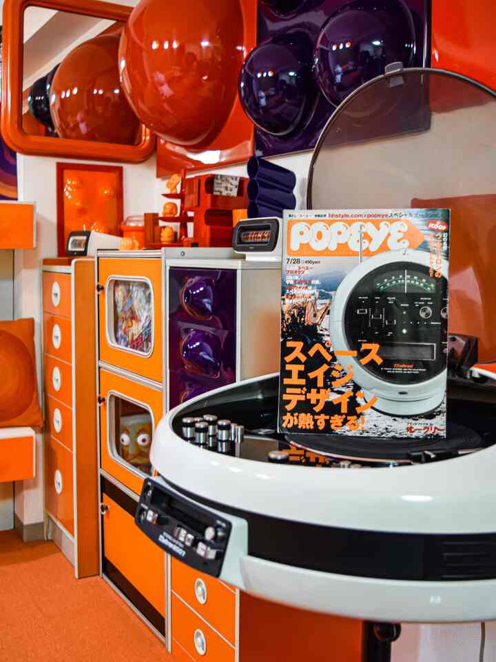 オレンジ色のトーンが特徴のスペースエイジスタイルのインテリア、ヴィンテージオーディオとPOPEYE雑誌が置かれた印象的で活気ある空間