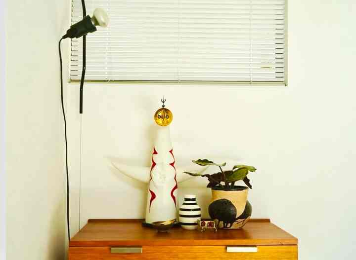 白い壁と茶色の木製ドレッサーが配置された、シンプルでモダンなオブジェのある空間