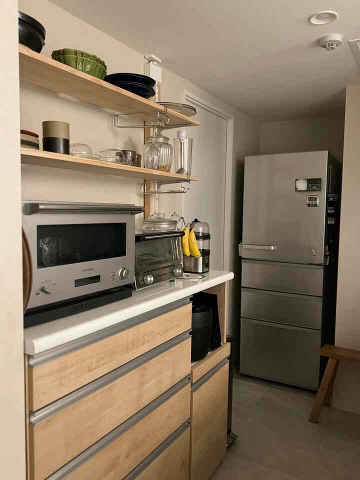 木目調と白い壁が調和するキッチン空間、オーブンや冷蔵庫などの主要家電が配置された清潔で雰囲気のあるインテリア