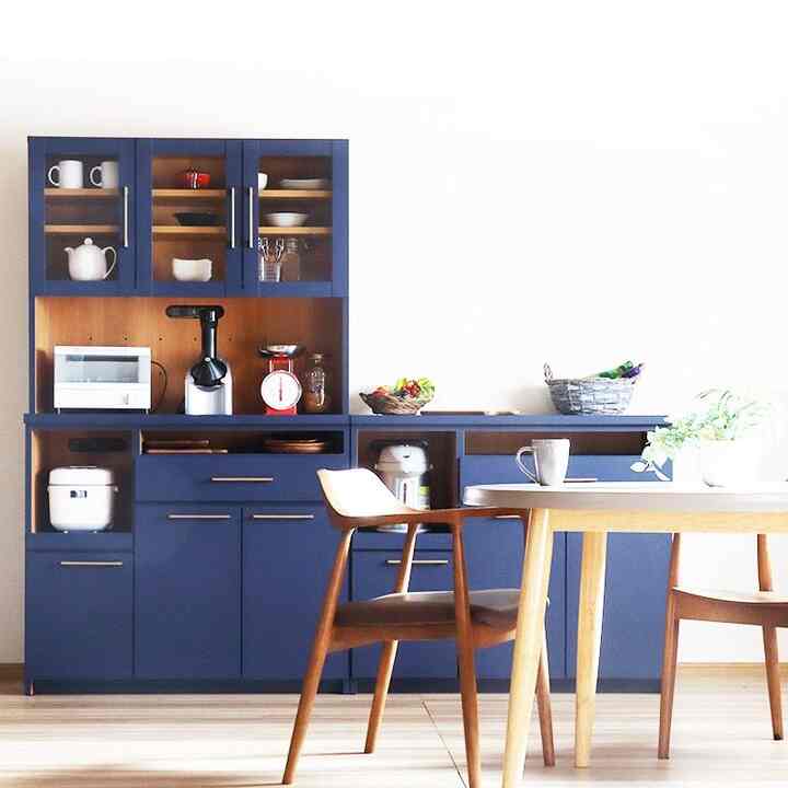 Bright kitchen dining area featuring navy storage cabinets and natural wood dining table and chairs with a clean aesthetic