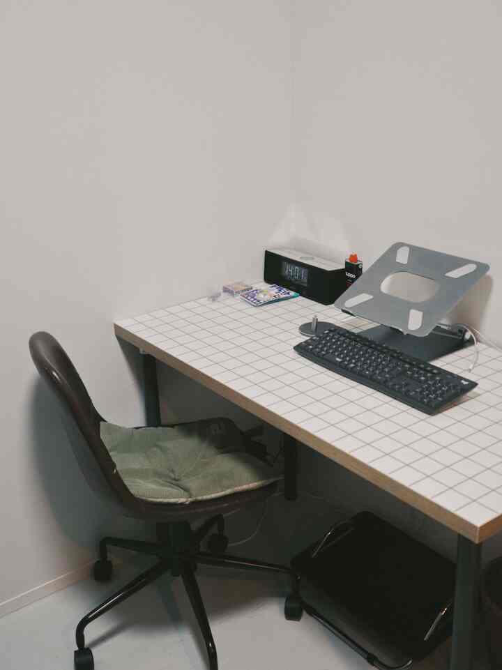 白とグレーの落ち着いたトーンの書斎、グリッド柄のデスクとオフィスチェアが配置されたシンプルなホームオフィス