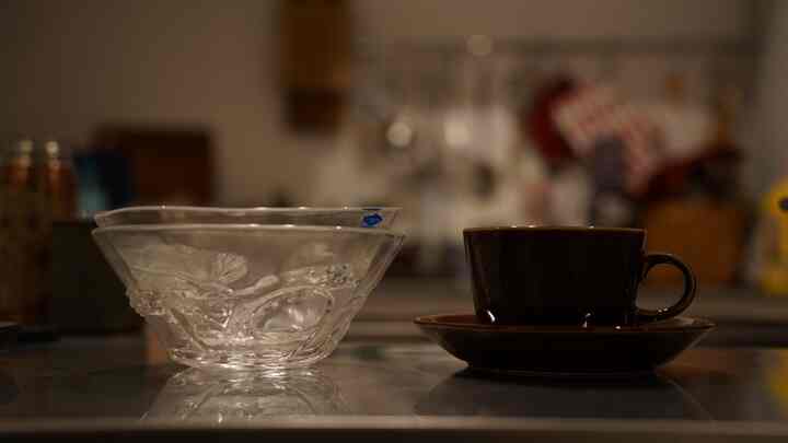 透明なガラスのボウルと黒いティーカップが置かれた、ヴィンテージ北欧スタイルのキッチンテーブルの上のアイテム