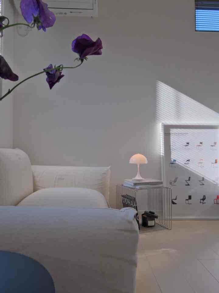 White-toned Nordic modern living room featuring a sofa and wire side table with lamp, creating a clean and spacious atmosphere