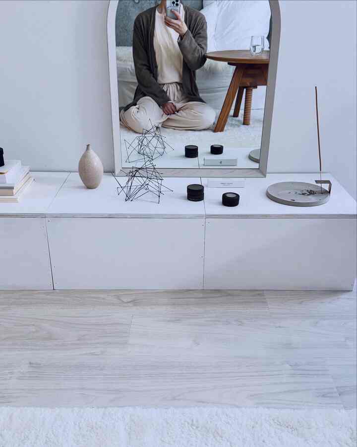 白とグレーのトーンのワンルーム、中央にアーチ型の鏡とコンソールテーブルが配置されたモダンで清潔感のあるインテリア