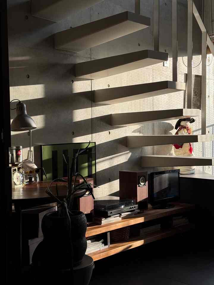 Warm wood tones and gray concrete wall harmonize in a Mid-Century Modern living room bathed in natural sunlight