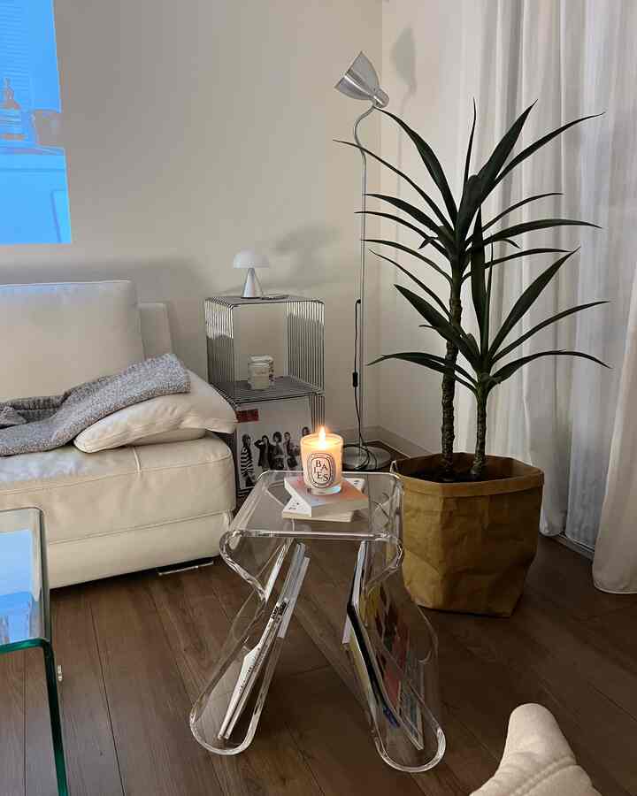 白と木目調のシンプルなリビング、アクリルスツールとフロアランプ、植物が配置されたナチュラルでモダンなインテリア