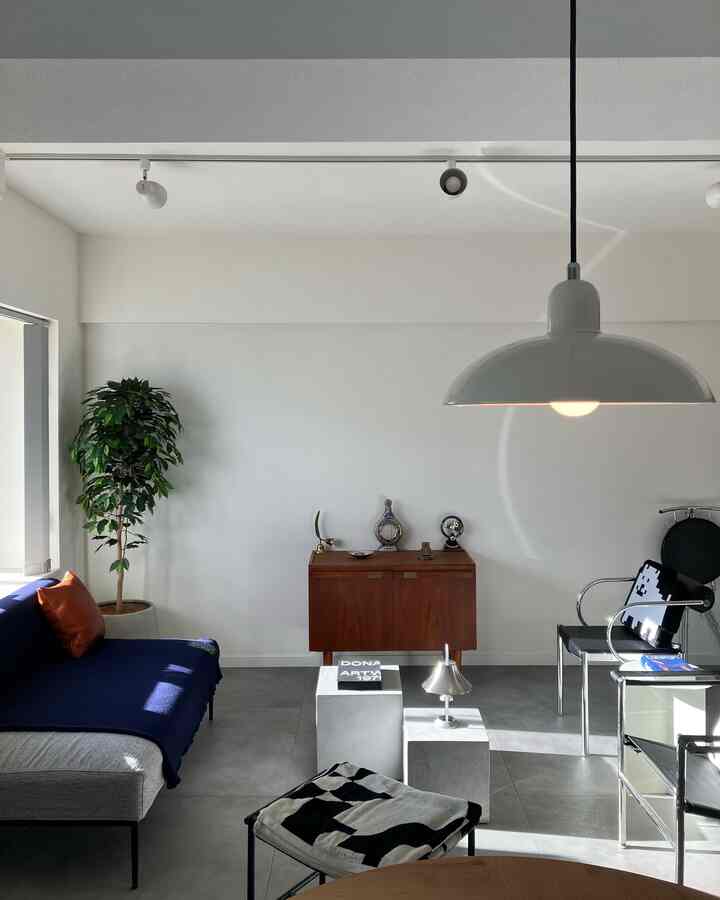 白い壁と天井に囲まれた、ミッドセンチュリーモダンの家具が配置されたシンプルで洗練されたリビング空間