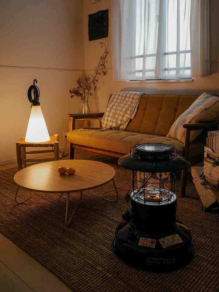 暖かみのある木目調のリビング、カリモク60のソファと丸いコーヒーテーブル、ストーブ、間接照明が配置された雰囲気のあるインテリア