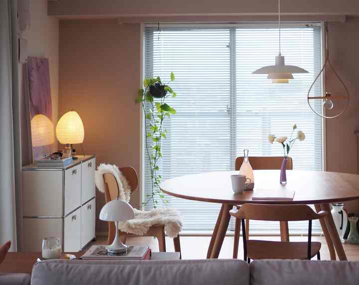 Natural tone dining room featuring a round wooden dining table, chairs, and soft pendant lighting creating a calm atmosphere
