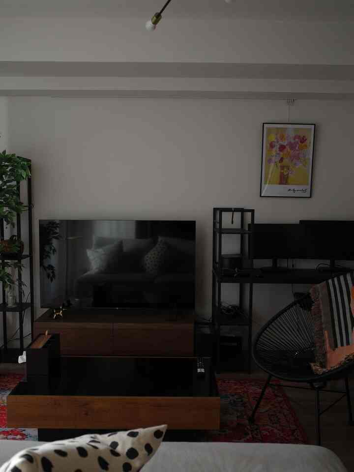 ブラウンとブラックの色調のリビング、テレビとコーヒーテーブル、棚と椅子が配置された印象的な空間