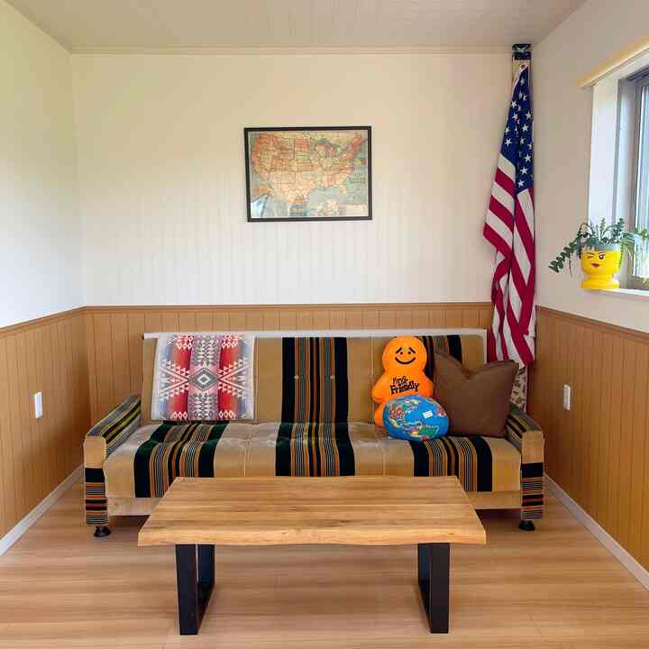 ブラウンと木目調のリビング、レトロなソファとアメリカ国旗、壁にアメリカ地図が配置された雰囲気のあるインテリア