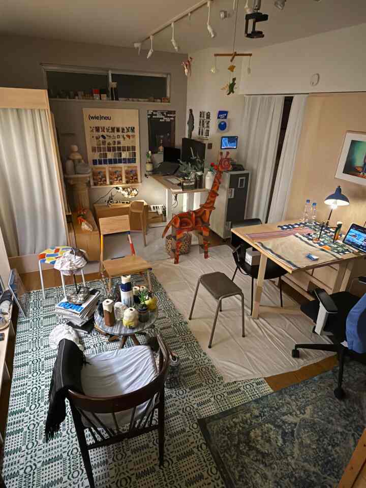 白とナチュラルカラーの一人暮らし用の小さな作業スペース、机とパーソナルチェア、ラグが配置された雰囲気のあるインテリア