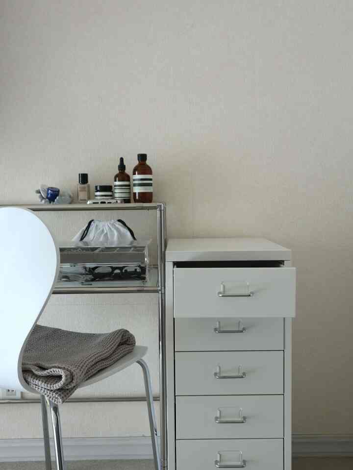 白とモノトーンの色調のシンプルなドレッサーとアクリルケースが配置された空間