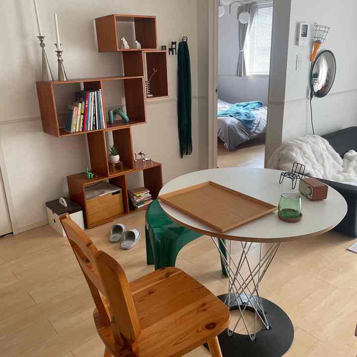 White and wood tone compact living room featuring mid-century modern bookshelf and table with cozy home cafe atmosphere