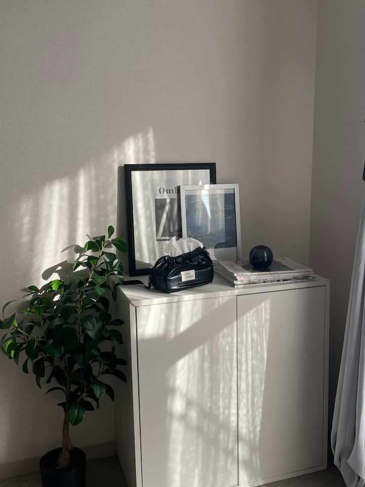 モノトーンのホワイトトーンが特徴の窓際に配置されたEKETキャビネットとシンプルでミニマルな一人暮らしのインテリア