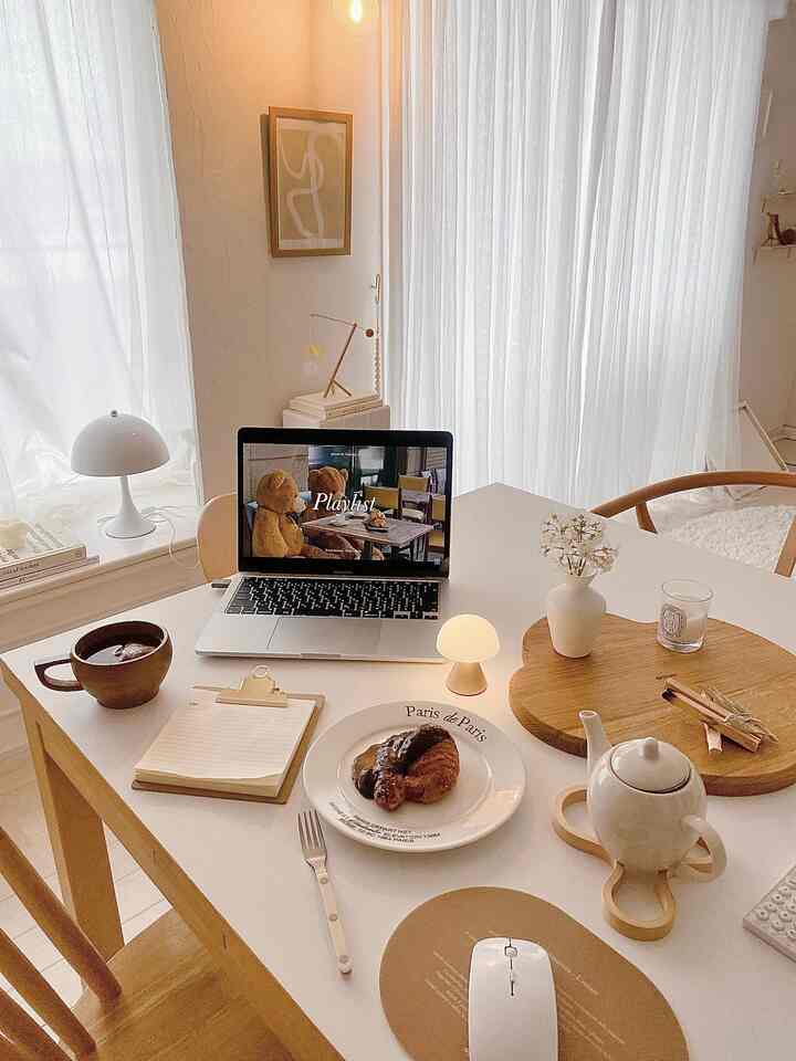 白と木目調が調和するダイニング、テーブル上にはホームカフェのアイテムとノートパソコンが置かれた印象的な一人暮らし空間