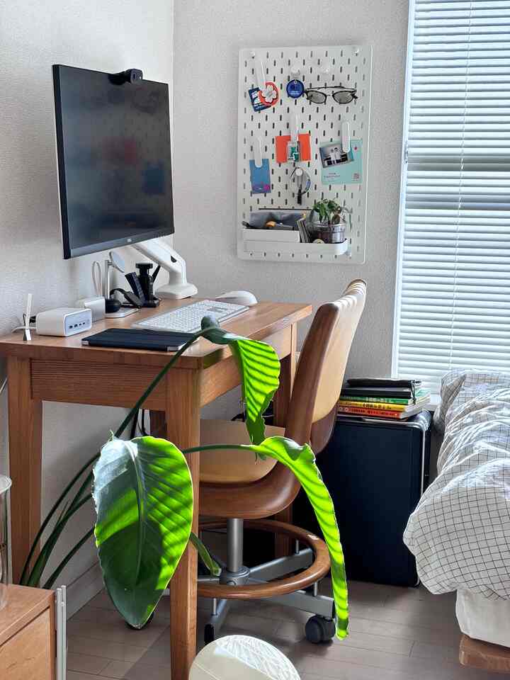 Bright wood-tone single household 1K home office space featuring a desk, office chair, monitor stand, and pegboard with a natural atmosphere