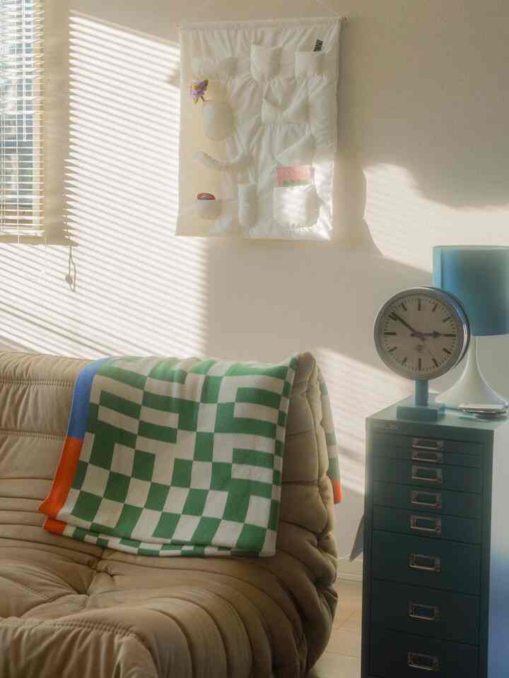 A living room with soft natural light featuring a beige sofa and green cabinet