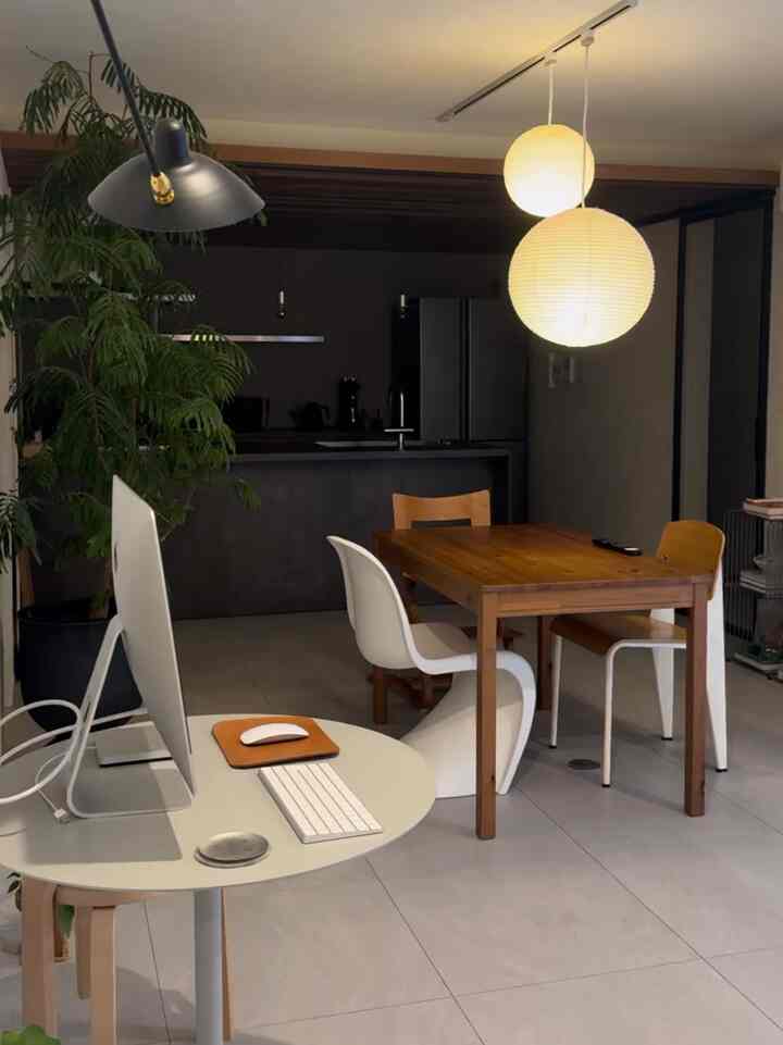 白い壁と木目調の家具が調和するダイニング、パソコンデスクとペンダントライトが配置された雰囲気のあるインテリア