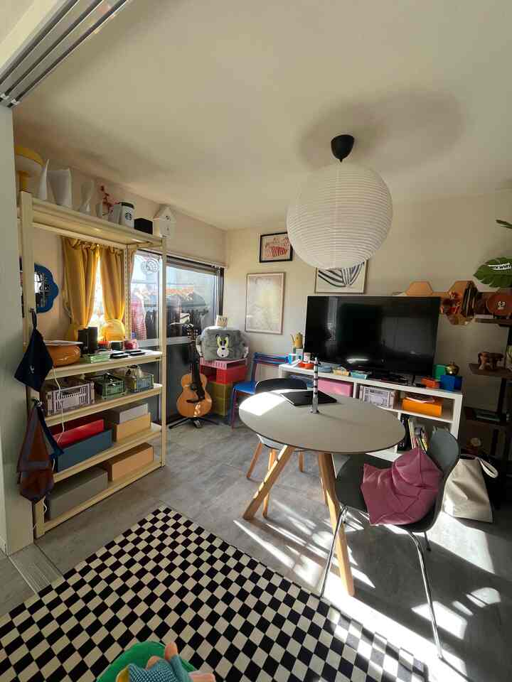 白と黄の色調の居心地の良いダイニングルーム、ミッドセンチュリーモダンの丸テーブルと多様な収納、ラグが配置された雰囲気のあるインテリア