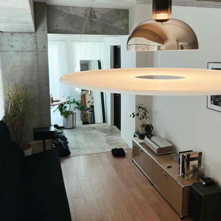 白と黒のトーンの狭くモダンなワンルームリビング、USM収納とソファ、照明が配置された印象的な空間