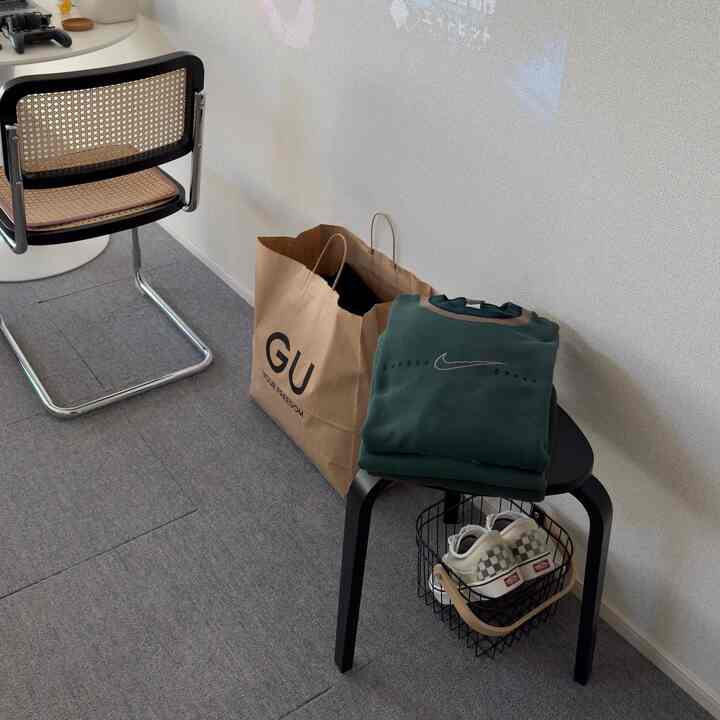 Gray carpeted small living room featuring black stool and chair with minimalistic setup