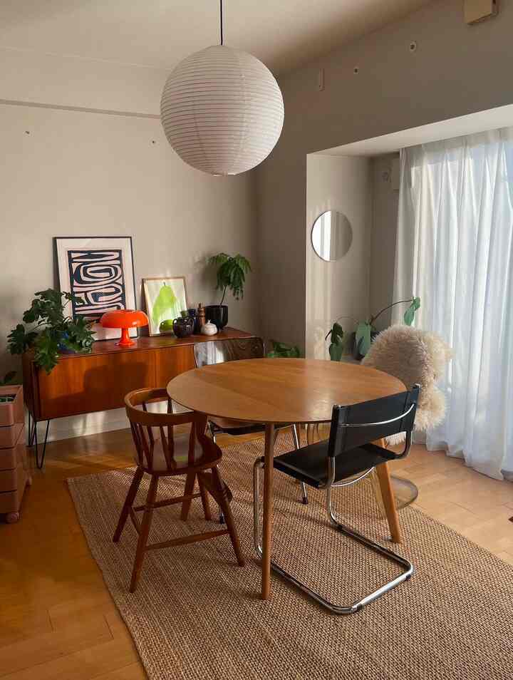 Natural wood tone dining room with orange accents, featuring vintage chairs and a sideboard in a cozy setting