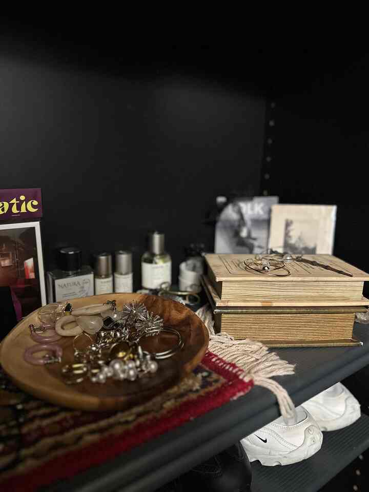 黒を基調とした玄関のシューズラック棚に木目調のアクセサリープレートと本が配置されたシンプルで整った収納空間