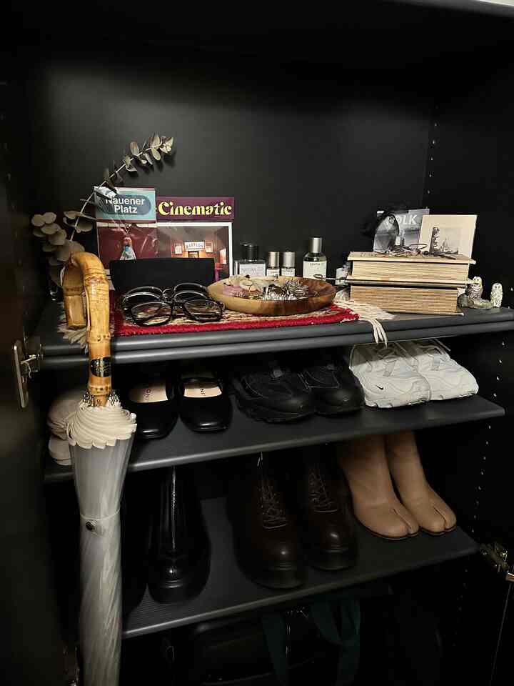 黒と木目調の玄関収納、様々な靴や傘、アクセサリーが整った雰囲気のあるインテリア