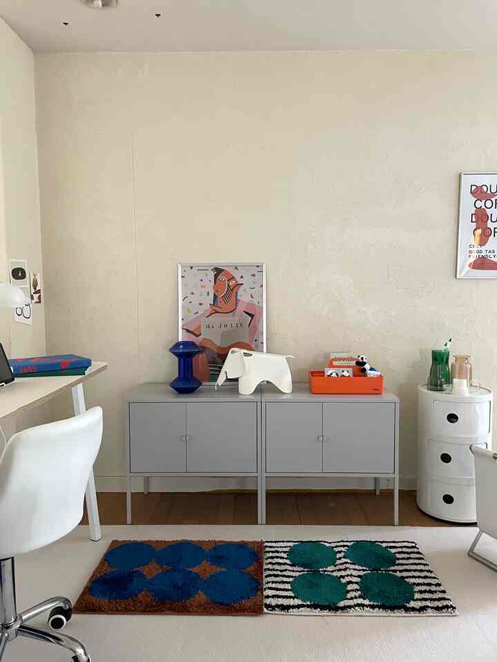 White and gray toned 1DK home office featuring two small patterned rugs and mid-century modern furniture in a tidy setting