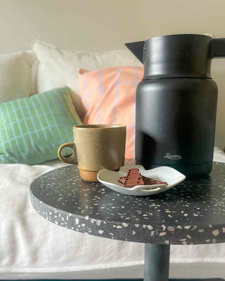 白と茶色のトーンの一人暮らし寝室、テラゾのサイドテーブルにカップとサーモジャグを配置した温かみのあるおうちカフェ空間