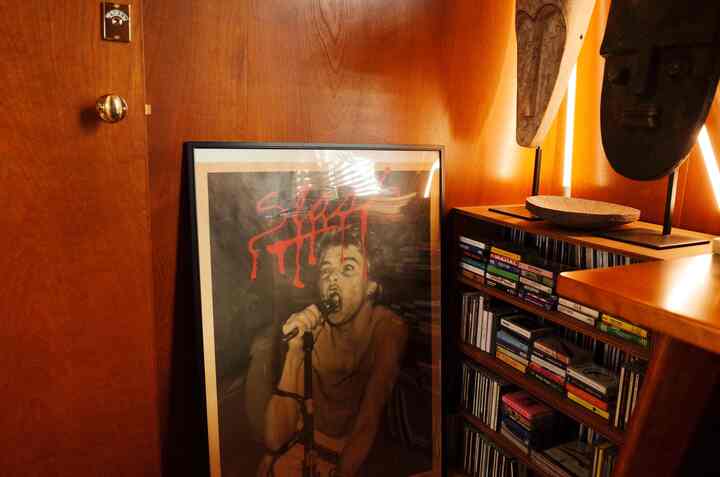 茶色の木目調壁と棚があるヴィンテージポスターとCD・カセットテープ収納の雰囲気あるインテリア