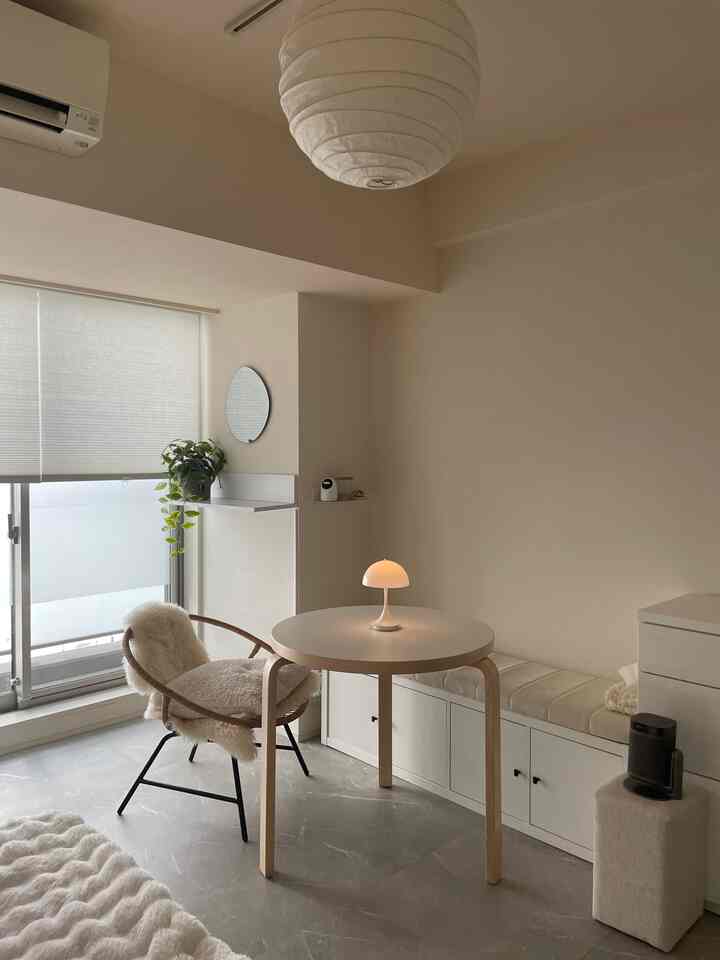 白とベージュのトーンのリビング、丸テーブルとアームチェアが配置されたミニマルで落ち着いたインテリア